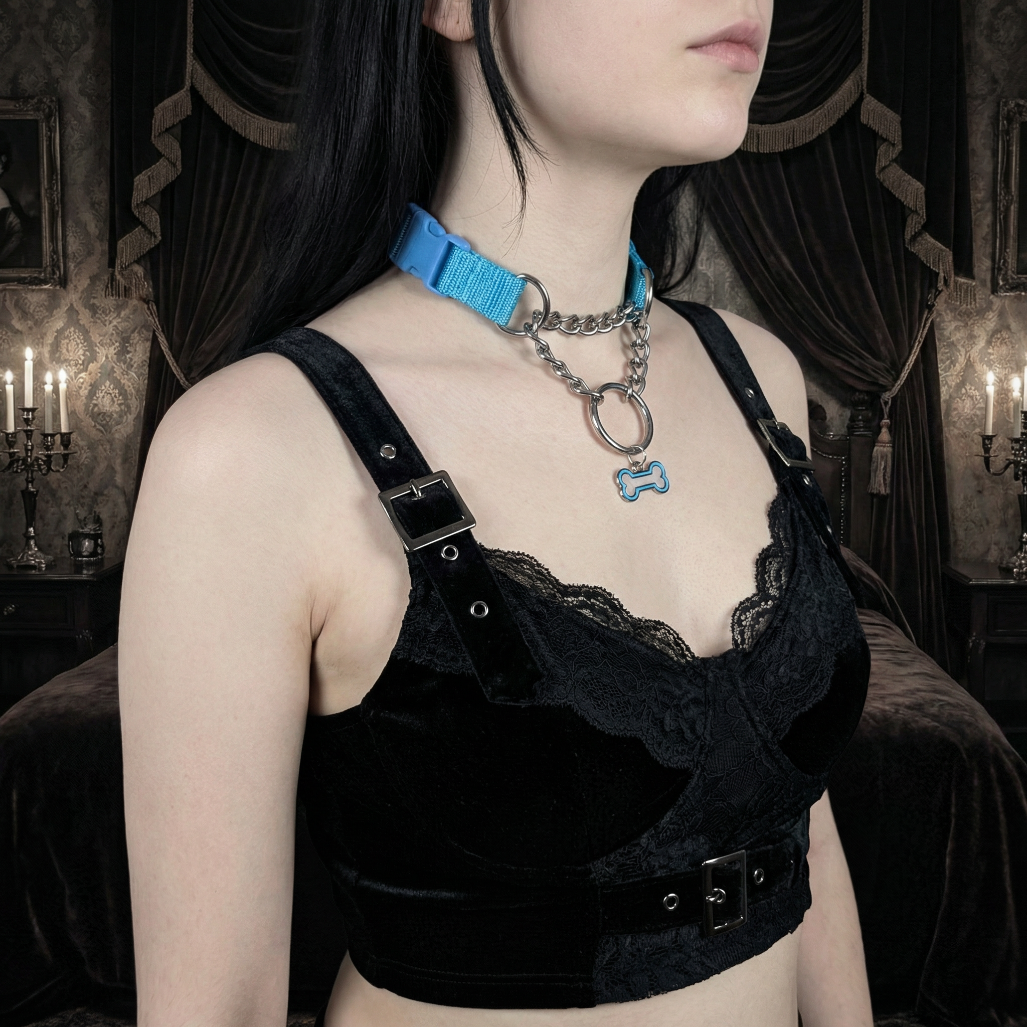 Person wearing a black lace top with a blue collar and chain in a dimly lit room.