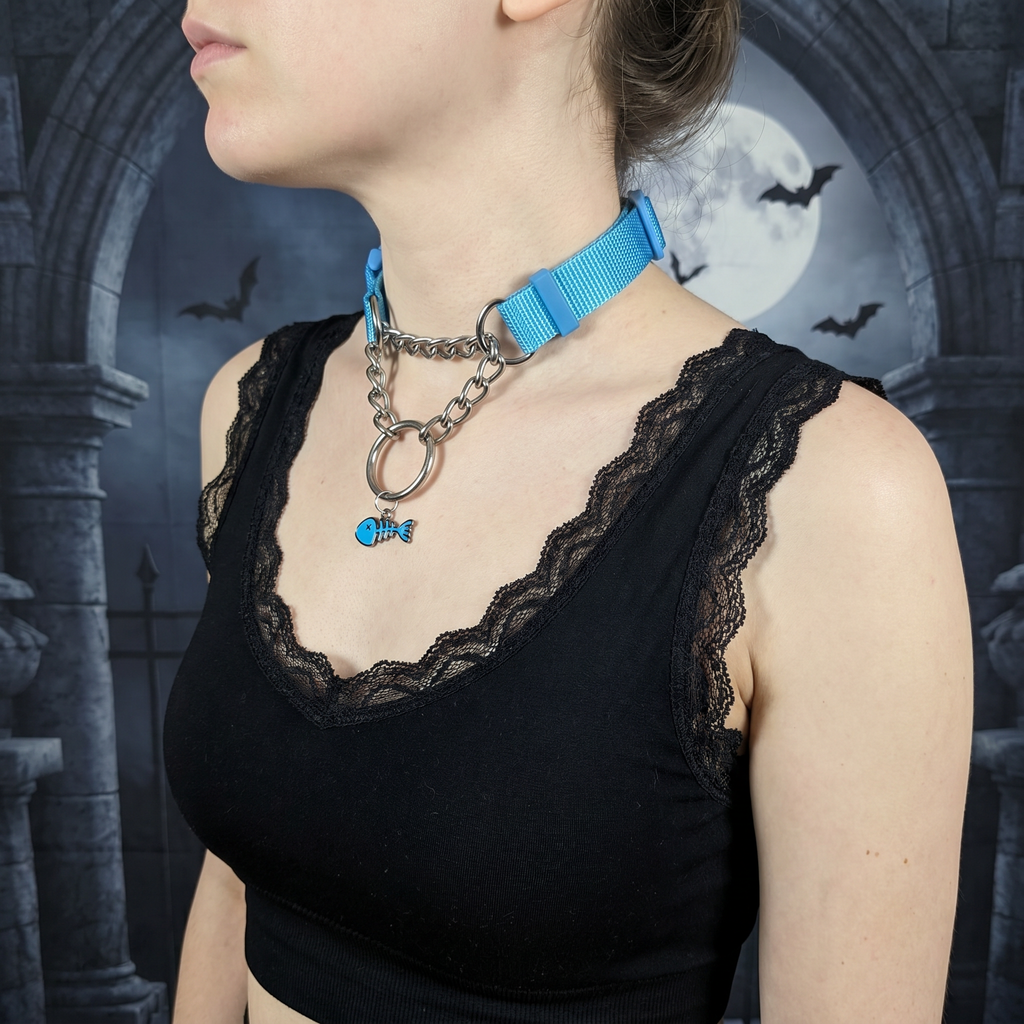 Person wearing a black lace top with a blue collar and chain necklace against a gothic-style background.
