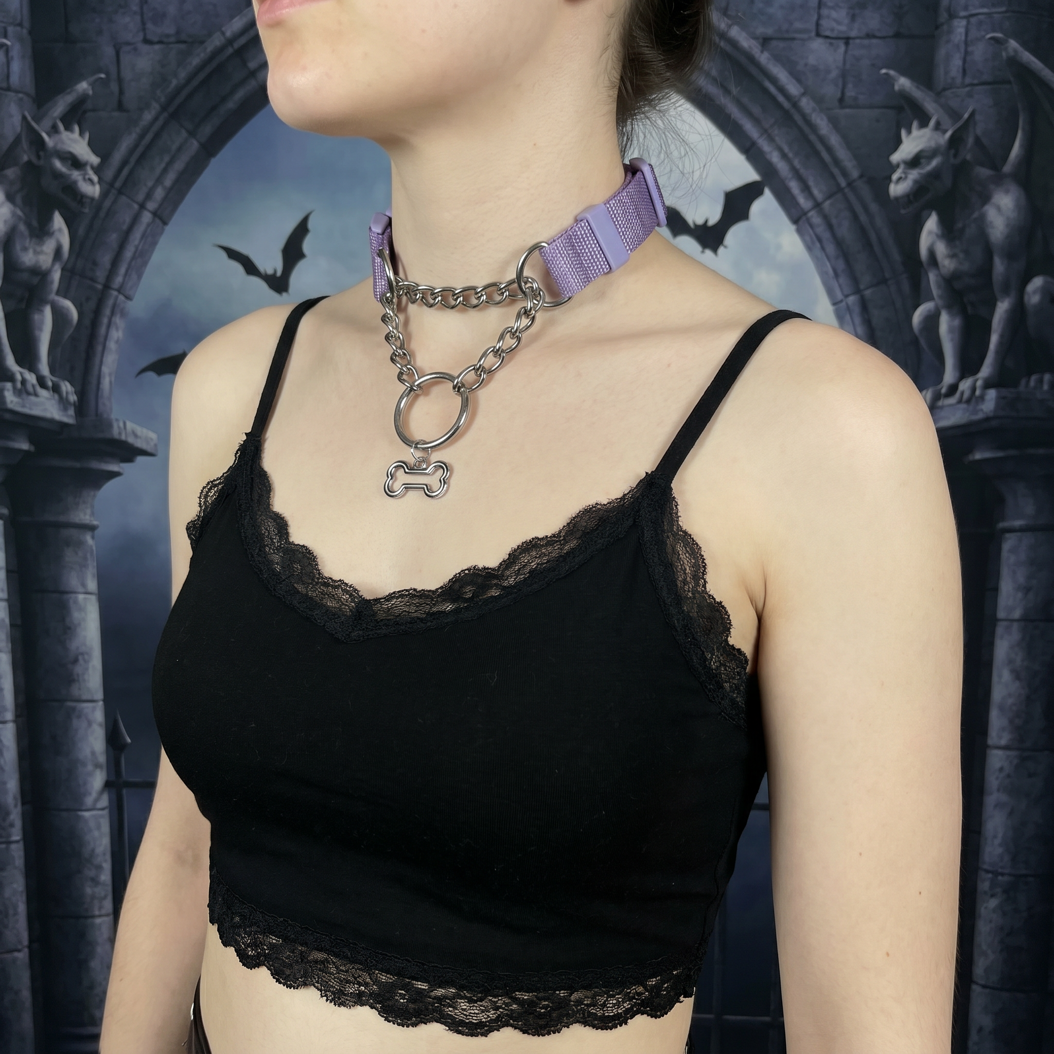 Person wearing a black lace top with a purple choker and chain necklace against a dark, gothic-style background.