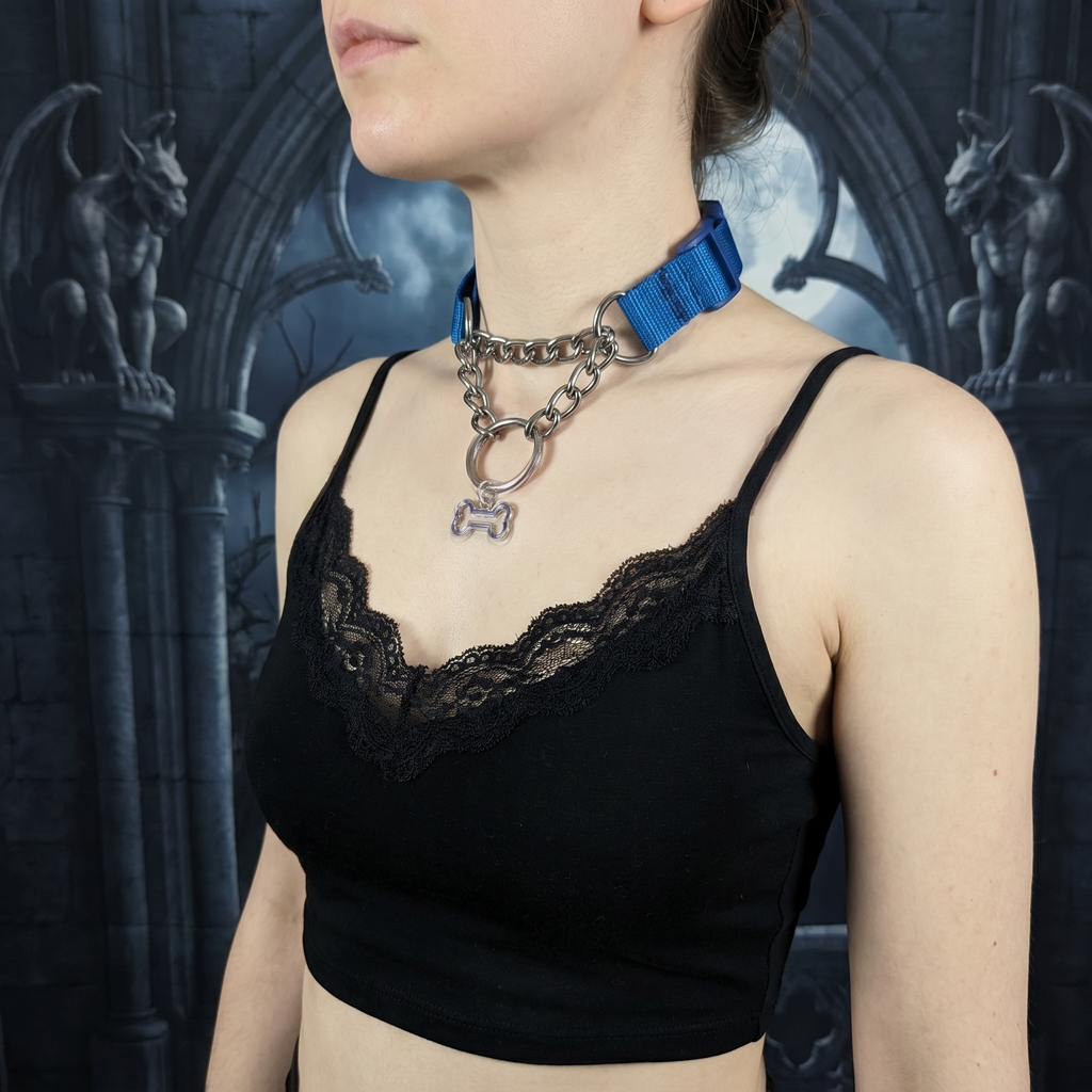 Person wearing a black lace top with a blue ribbon and chain necklace against a dark, gothic-style background.