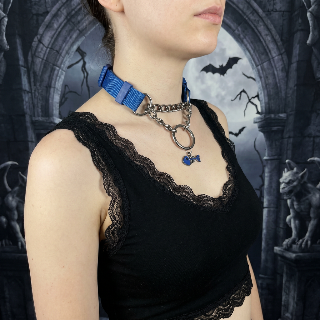Person wearing a black lace top with a blue ribbon and chain necklace against a dark, gothic-style background.