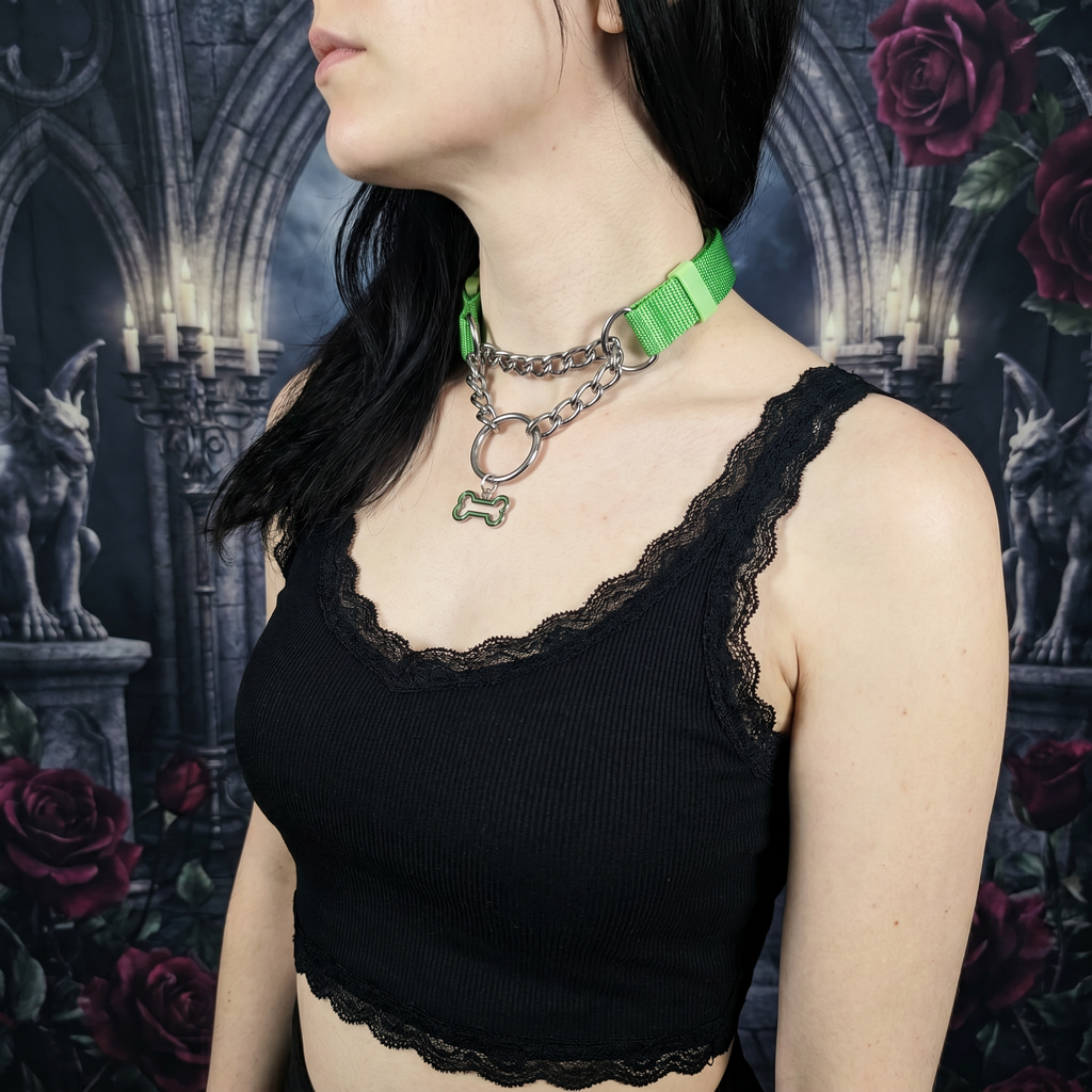 Person wearing a black lace top with a green collar against a dark, gothic-style background with roses and statues.