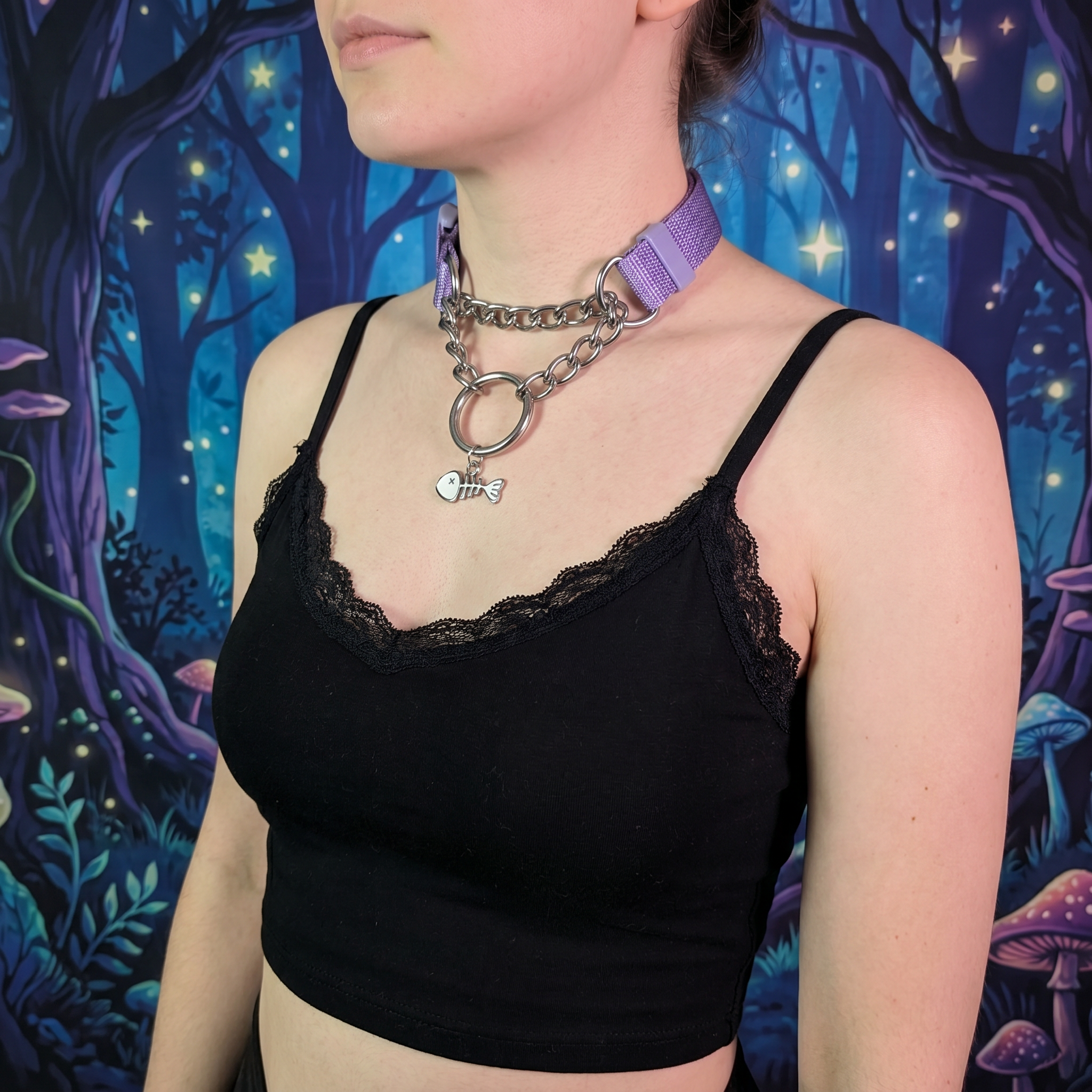 Person wearing a black lace top with a colorful forest background