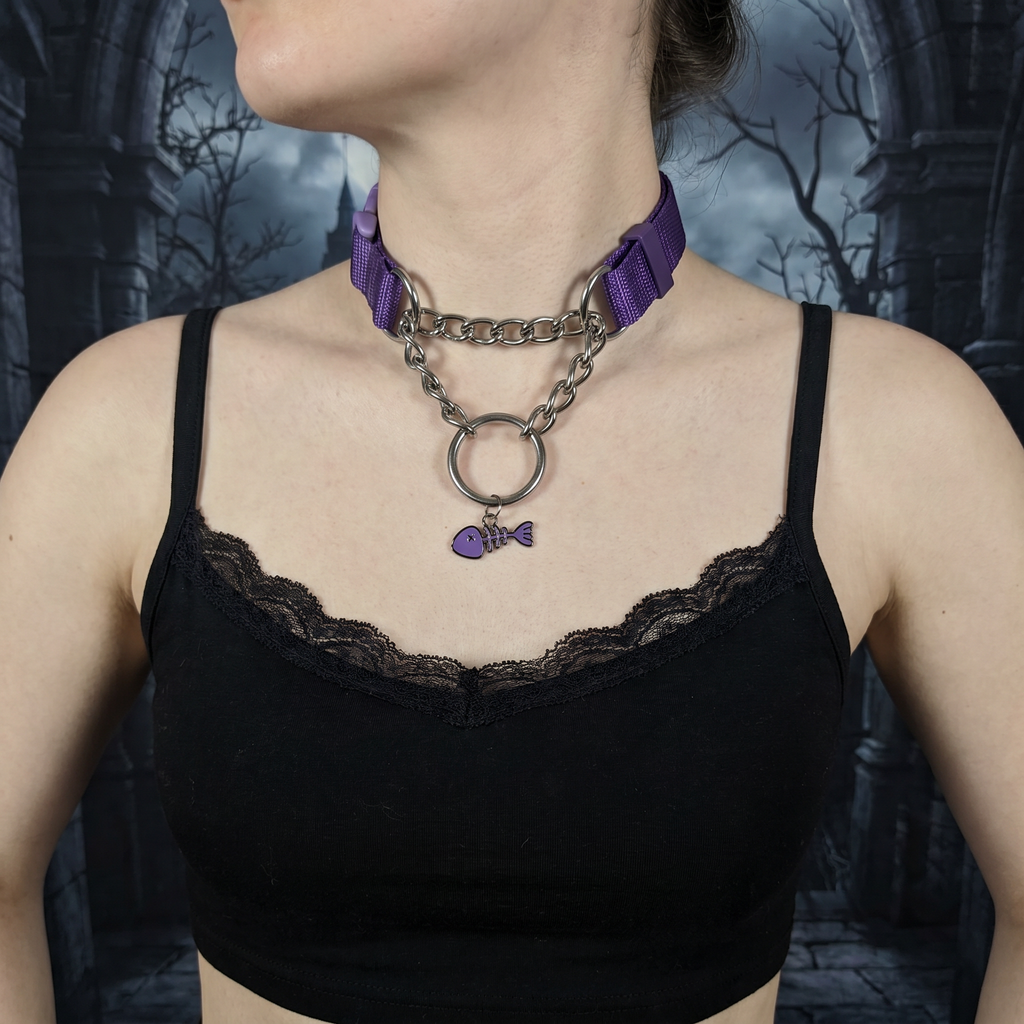  Person wearing a black lace top with a purple ribbon and chain necklace against a dark, gothic-style background.