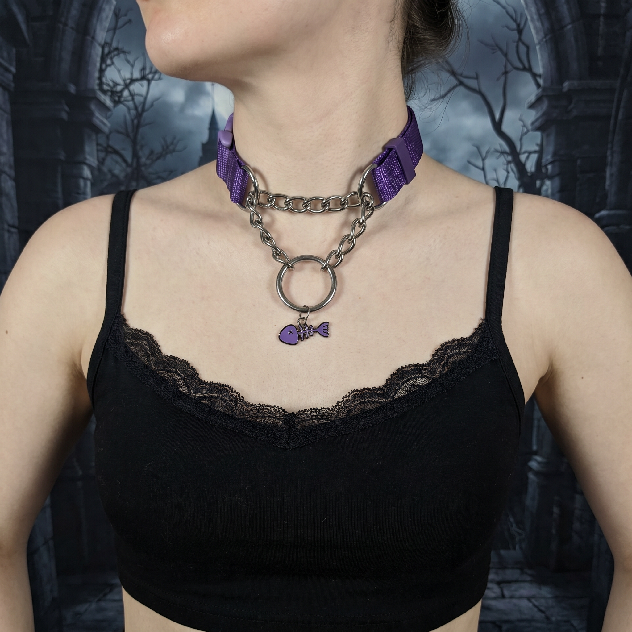  Person wearing a black lace top with a purple ribbon and chain necklace against a dark, gothic-style background.