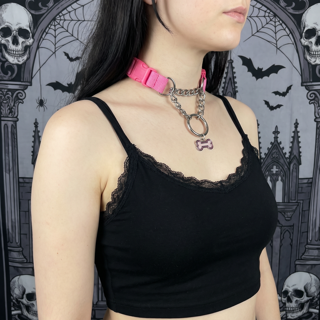 Person wearing a black lace-trimmed top with a pink choker against a gothic-style background.